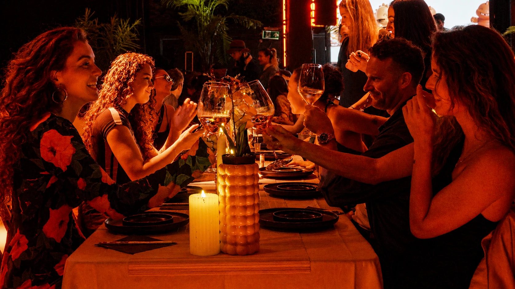 Guests raising their glasses at a candlelit Arigato Show dinner table