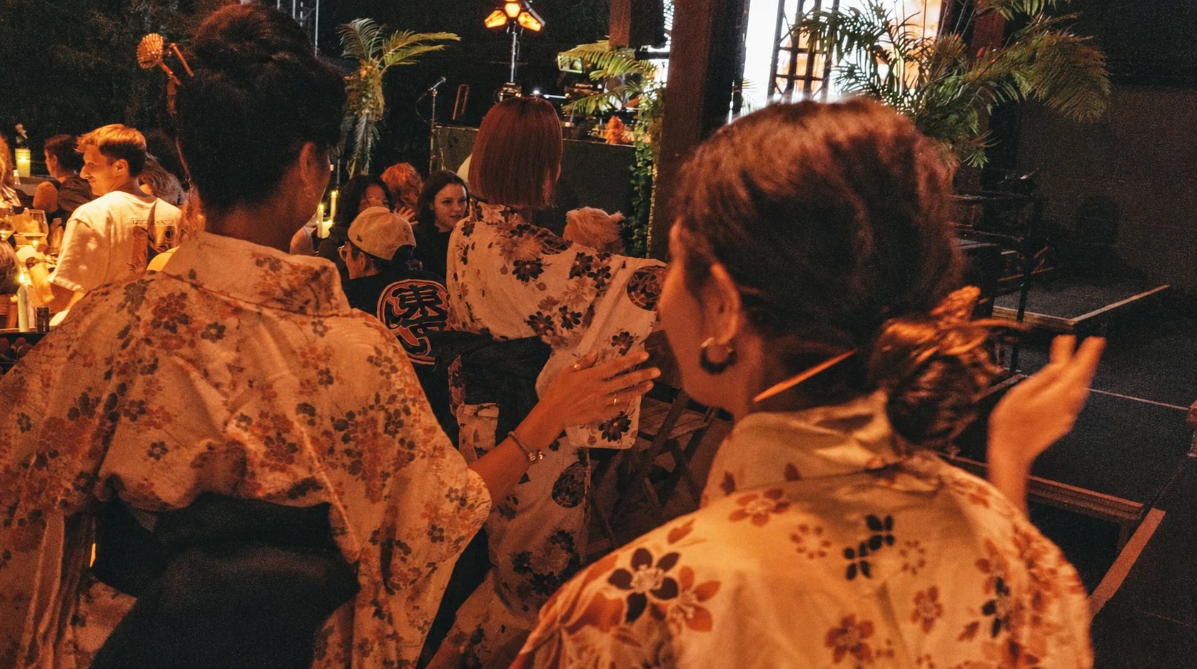 Hosts in yukata clapping along between the tables at an Arigato Show